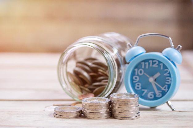 Cierre el ahorro de dinero en un frasco de vidrio y un despertador para obtener dinero en efectivo en inversiones futuras