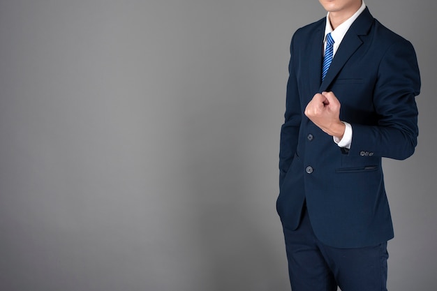 El cierre para arriba del hombre de negocios en el traje azul es acertado en fondo gris