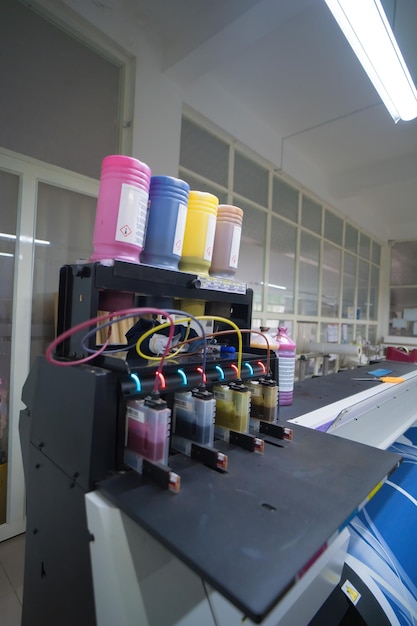 Cierre las botellas de tinta CMYK de una impresora de sublimación Fábrica interior Máquina de impresión grande para el negocio del papel en la sala de impresión Concepto de sublimación