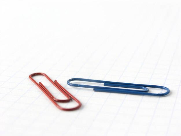 Foto cierre los clips de papel azules y rojos en el fondo del cuaderno