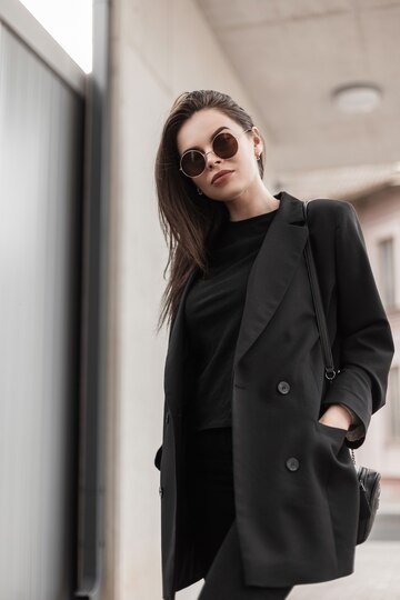 Cierre el cuerpo de la mujer en traje juvenil casual negro de moda. mujer  joven moderna en blazer de moda en elegante camiseta negra se encuentra en  la calle en la ciudad.