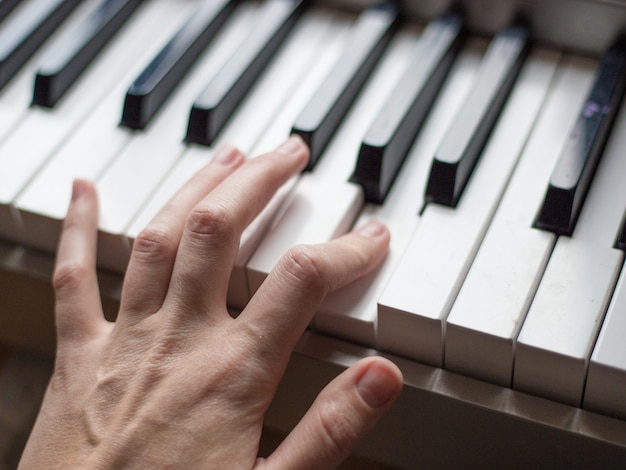 Cierre los dedos del pianista en las teclas del piano, los brazos tocan solo de música o una nueva melodía. Manos de músico masculino jugando en el sintetizador.