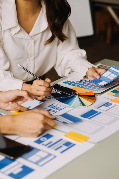 Cierre el desarrollador de ux y el diseñador de ui intercambiando ideas sobre el diseño de estructura alámbrica de la interfaz de la aplicación móvil en la mesa con el resumen del cliente y el código de color en la oficina modernaAgencia de desarrollo digital creativa