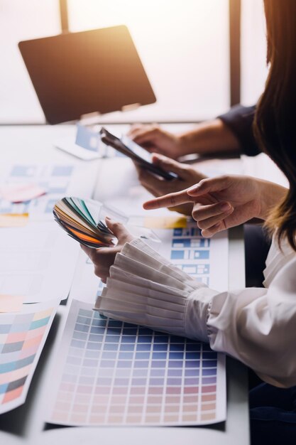 Cierre el desarrollador de ux y el diseñador de ui intercambiando ideas sobre el diseño de estructura alámbrica de la interfaz de la aplicación móvil en la mesa con el resumen del cliente y el código de color en la oficina modernaAgencia de desarrollo digital creativa