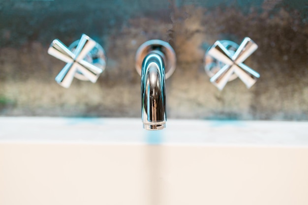 Cierre el grifo plateado de metal cromado con baño de cerámica blanca en el fondo de la pared del baño de lujo