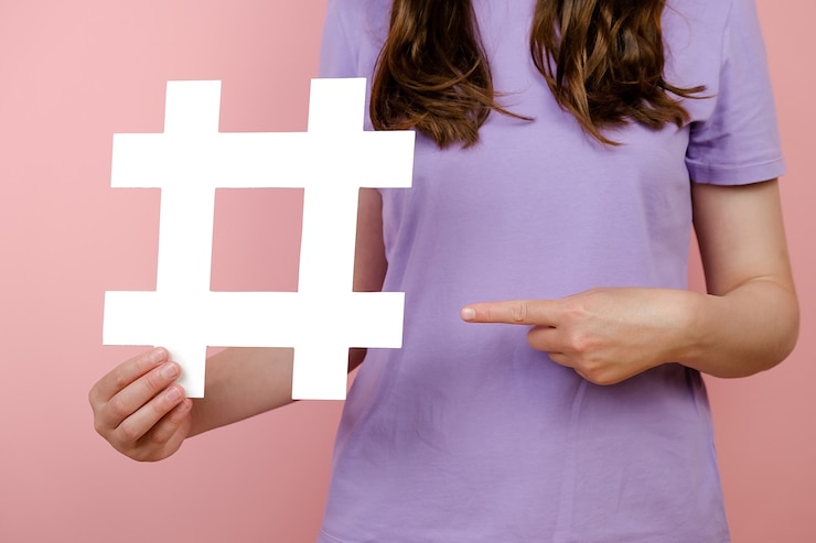 Foto cierre de hembra joven recortada sosteniendo un gran cartel de hashtag blanco, contenido web viral, promoción de internet, aislado sobre fondo de color rosa en el estudio. concepto de estrategia de sitio web de blog de blogs