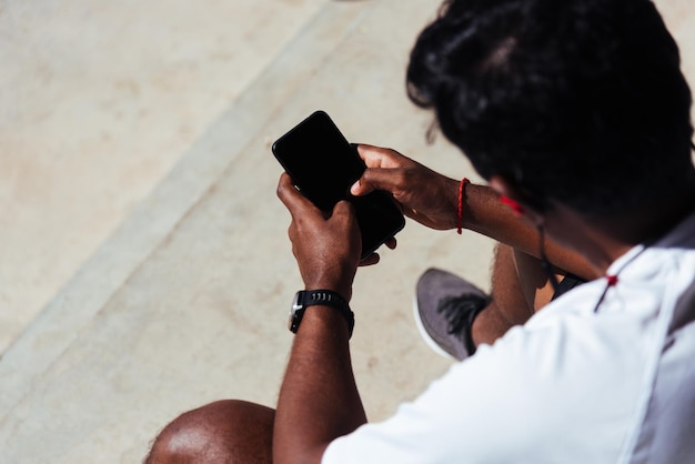 Cierre el joven atleta asiático, corredor deportivo, hombre negro, use un reloj inteligente de tiempo moderno y sincronícelo con un resultado de ejecución de verificación de teléfono inteligente después de la carrera de entrenamiento en la tecnología de entrenamiento de ejercicio saludable al aire libre