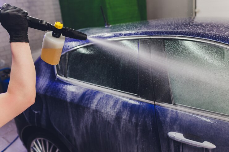 Foto cierre de limpieza de automóviles con agua a alta presión, lavadora de chorro de alta presión en proceso de lavado de automóviles.