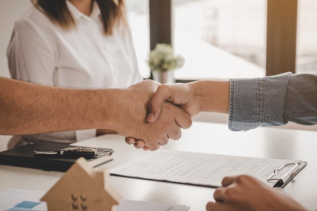 Foto cierre la mano de la casa, el agente de apartamentos o el apretón de manos del agente inmobiliario con el nuevo propietario, el inquilino o el alquiler. después de que el banquero haya aprobado y firmado el acuerdo de contrato de compra con éxito. concepto de propiedad.