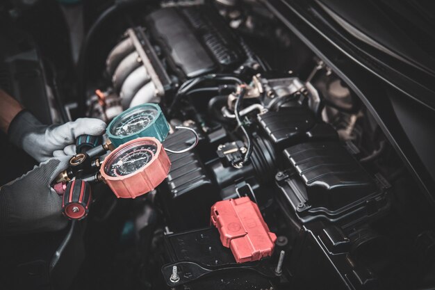 Cierre la mano del mecánico usando un manómetro múltiple para comprobar el acondicionador de aire del coche refrigerante