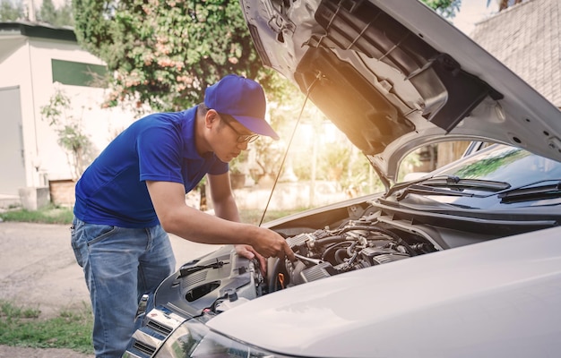 Cierre el mecánico de automóviles asiático que trabaja en el servicio de reparación de garaje