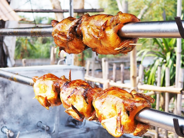 Cierre de pollo a la pimienta a la parrilla en la máquina giratoria de acero. Comida tradicional en la carretera en Tailandia.