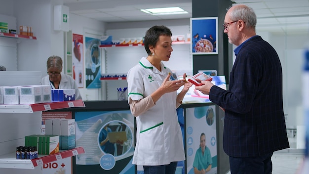 Cierre los productos farmacéuticos en los estantes de las boticas. Foto reveladora de un farmacéutico experto discutiendo con clientes de edad avanzada sobre el medicamento ideal para prevenir ataques cardíacos.