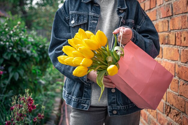 Cierre un ramo de tulipanes amarillos en manos de una niña