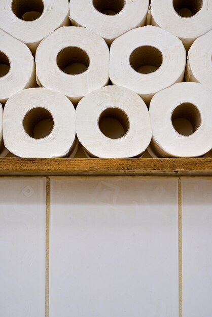 Cierre los rollos de papel higiénico en un estante de madera en un baño.