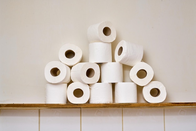 Cierre los rollos de papel higiénico en un estante de madera en un baño.