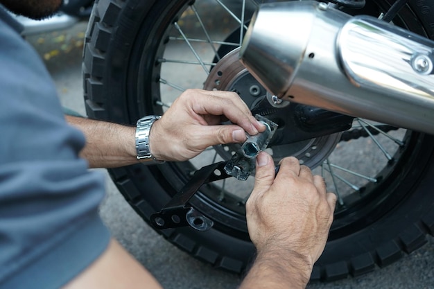 Cierre la rueda de la motocicleta fijada a mano del trabajador técnico en el exterior del garaje