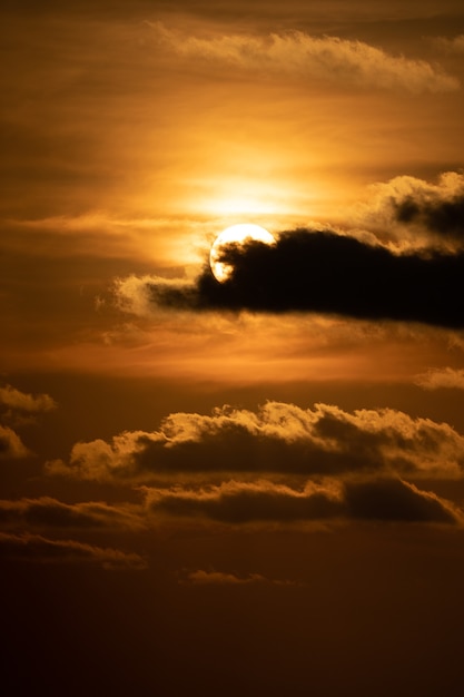 Cierre el sol con una nube frente a él en el crepúsculo del atardecer.