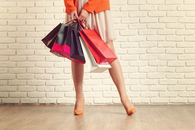 Cierre de tiro de pierna de mujer joven con coloridos bolsos de compras