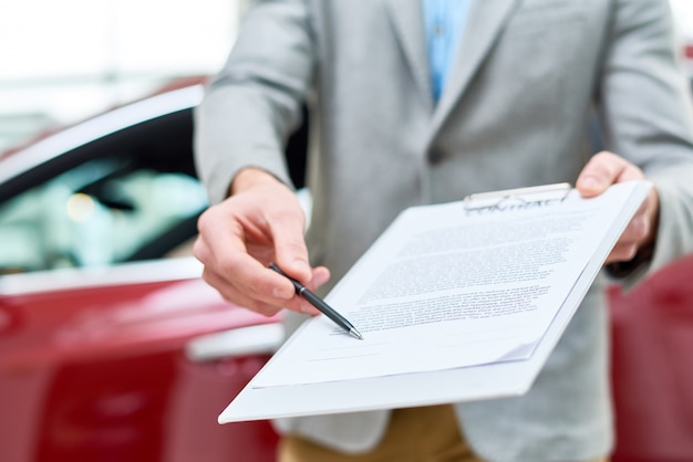 Foto cierre de vendedor de automóviles entrega contrato al cliente