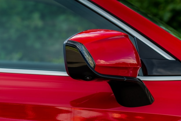 Cierre la vista frontal del espejo lateral del coche. Espejo retrovisor delantero en la ventanilla del automóvil. Detalles exteriores del coche. Espejo de coche rojo.
