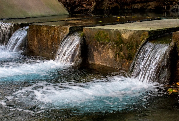 Foto ciérrese para arriba de aliviadero concreto viejo en el río en el bosque tropical.