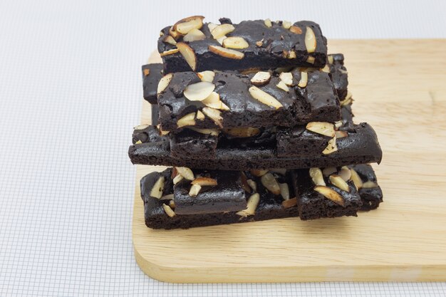 Ciérrese para arriba de brownies del chocolate de la torta con las nueces en la placa de madera y el fondo blanco