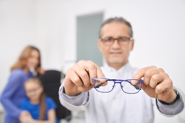 Ciérrese para arriba del doctor azul de los vidrios que se sostiene en manos.