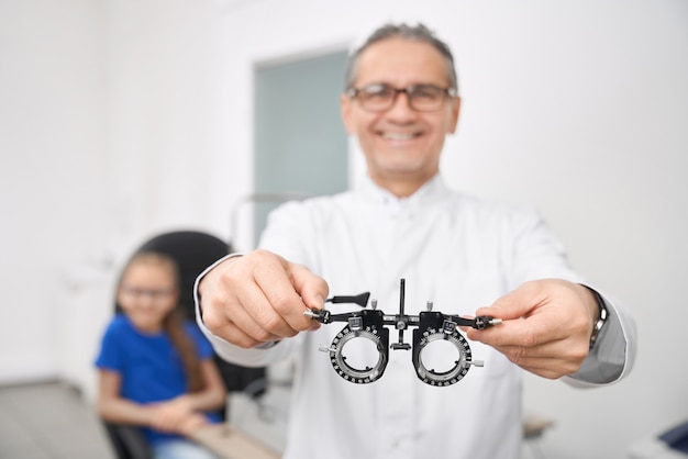 Ciérrese para arriba del doctor de la oftalmología que sostiene los vidrios de prueba del ojo.