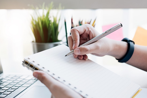 Ciérrese para arriba de la escritura del hombre en libreta.