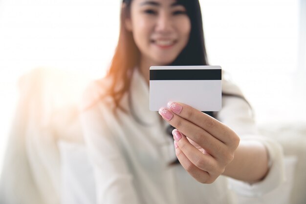 Ciérrese para arriba de la explotación agrícola de la tarjeta de crédito de la mujer asiática de la belleza. Las compras en línea