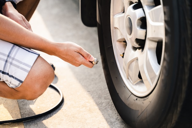 Ciérrese para arriba del hombre asiático que infla el neumático en la gasolinera.