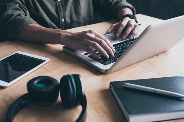 Ciérrese para arriba de hombre casual que usa la computadora portátil en el escritorio en casa.