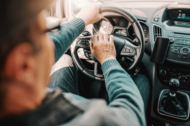 Ciérrese para arriba del hombre mayor que conduce su coche.