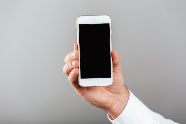 Ciérrese para arriba del hombre que muestra el teléfono móvil de la pantalla en blanco