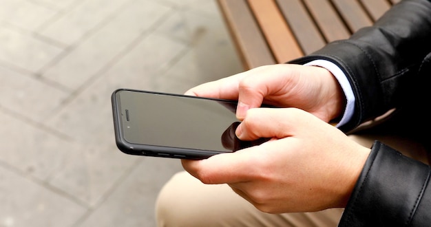 Ciérrese para arriba de un hombre que usa el teléfono elegante móvil.