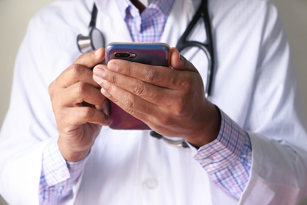 Ciérrese para arriba de la mano del doctor usando smartphone en el hospital.