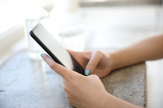 Ciérrese para arriba en la mano de la mujer que sostiene acciones y datos comerciales del smartphone en concepto del negocio de la cafetería