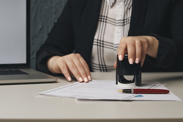 Ciérrese para arriba en la mano del notario público de la mujer que sella el documento. Concepto de notario público.