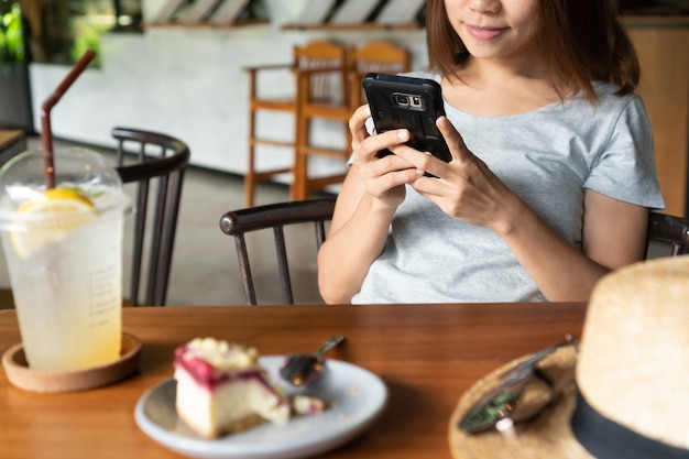 Ciérrese para arriba de las manos de las mujeres que sostienen el teléfono móvil en café.