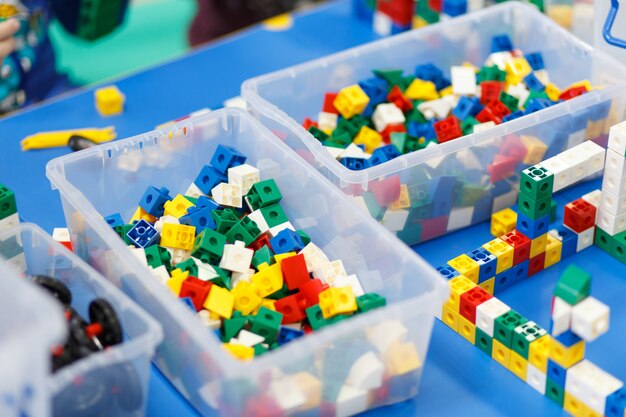 Ciérrese para arriba de las manos del niño que juegan con los ladrillos plásticos coloridos en la tabla.