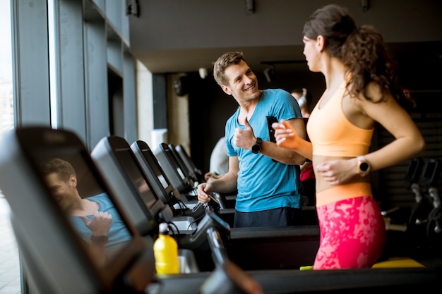 Ciérrese para arriba de mujer con el instructor que se resuelve en la rueda de ardilla en gimnasio