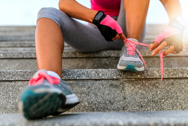 Ciérrese para arriba de la mujer que ata los cordones afuera durante el día.