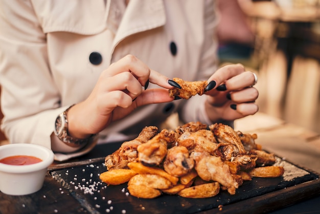 Ciérrese para arriba de la mujer que come las alas de pollo.