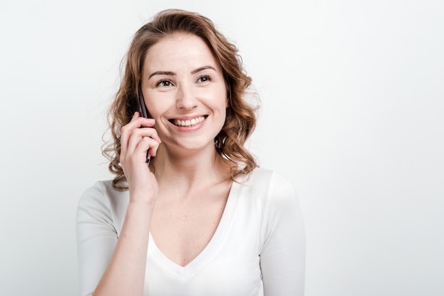 Ciérrese para arriba, mujer sonriente que habla en el teléfono.