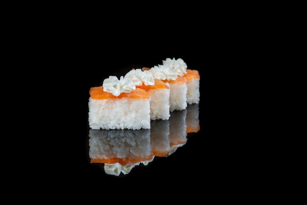 Ciérrese para arriba del rollo de sushi en una pared negra. Plato japonés