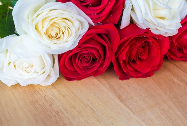 Ciérrese para arriba de rosa roja y blanca fresca en el escritorio de madera