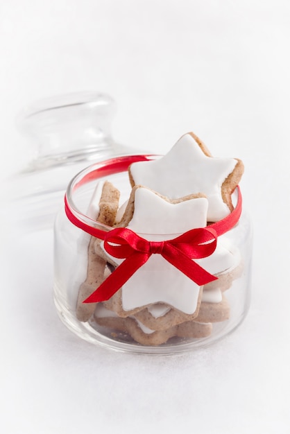 Ciérrese para arriba de un tarro de cristal lleno con las galletas caseras de la estrella de la Navidad.