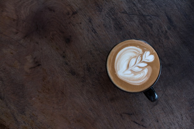 Ciérrese para arriba de la taza de café caliente del arte del latte en la tabla de madera