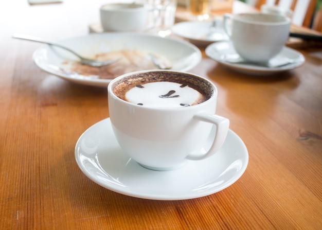 Ciérrese para arriba de la taza de café caliente del arte del latte en la tabla de madera